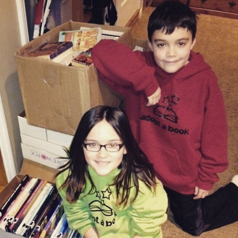 Hannah and Alex Laman sit with boxes of books as young children. 