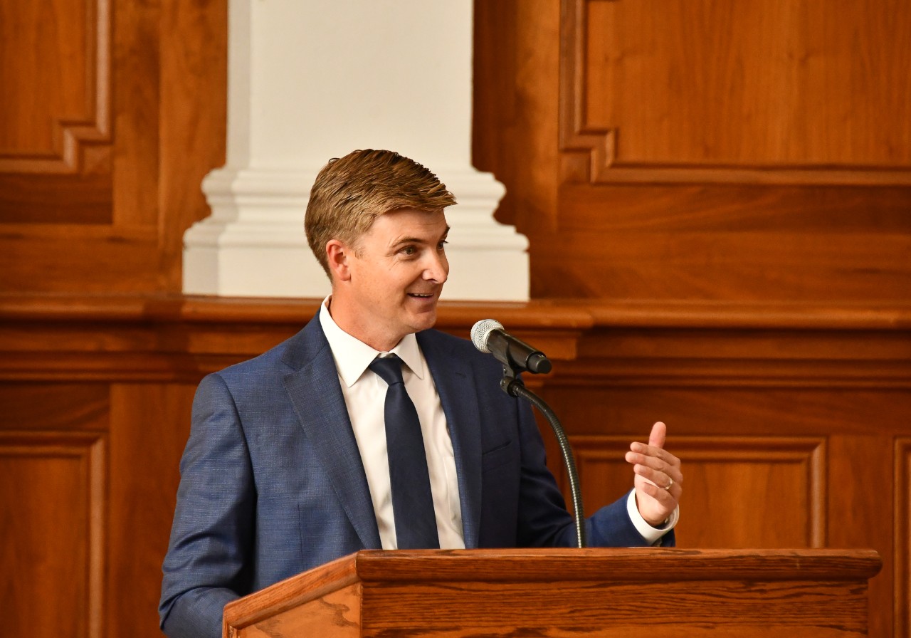 Andrew Lewis stands at a podium.