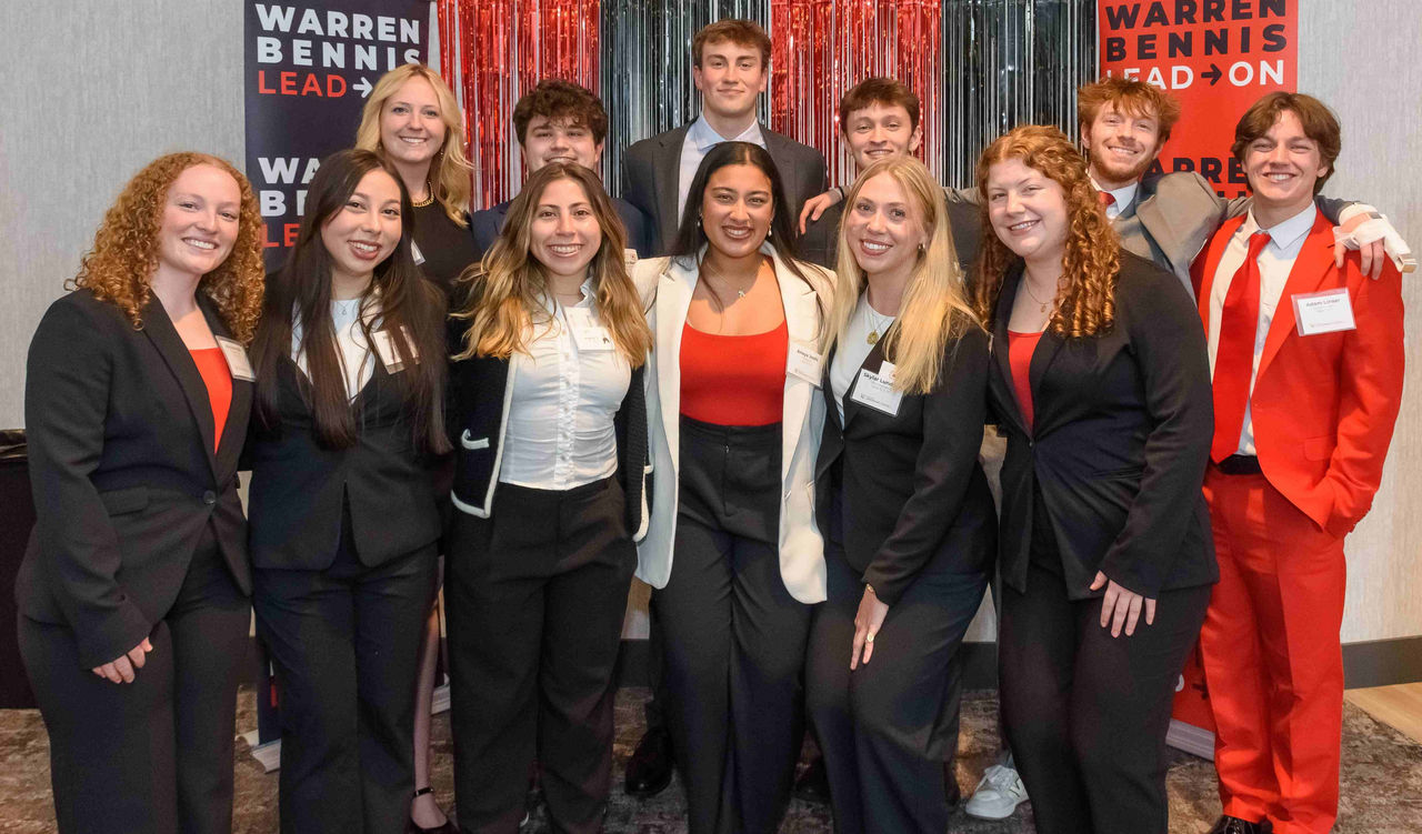 Students dressed in red, white and black professional dress gather for a photo.