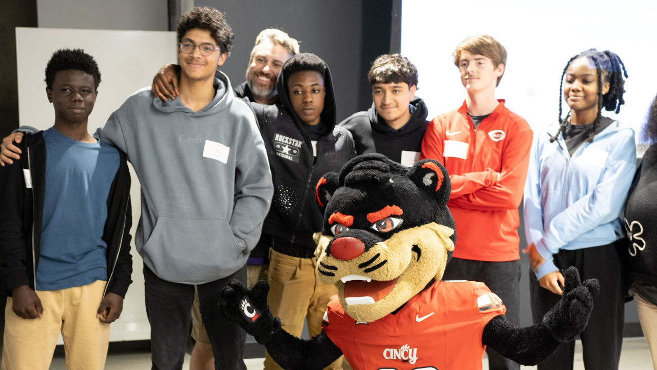 Students at the RAISE AI Summit pose with the Bearcat. 