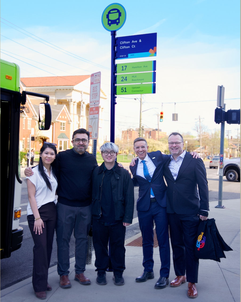 Collaborators smile infront of the Cincinnati Metro bus stop.