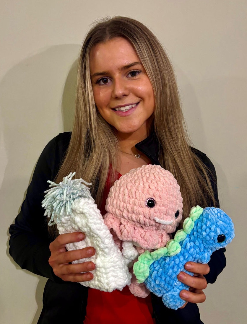 Katelin Maulden holding crocheted hats and toys