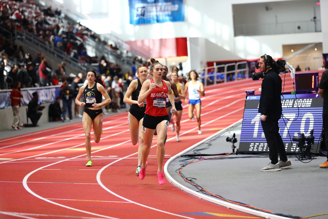 Juliette Laracuente-Huebner runs ahead of a pack of other runners on an indoor track