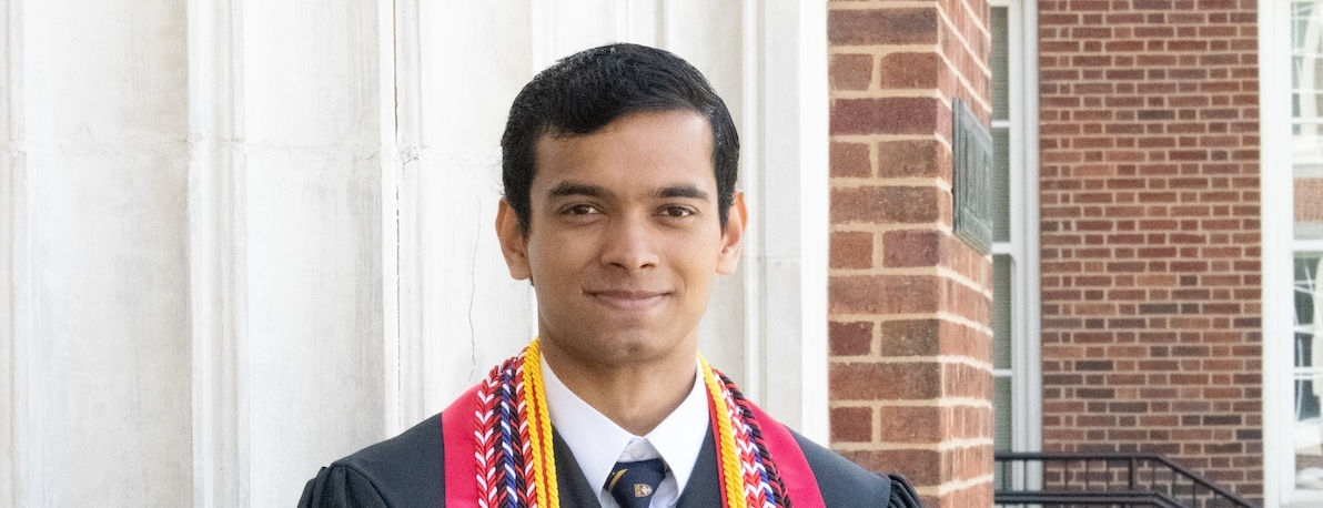 Thavishka Gamage wears a graduation gown and cords. 