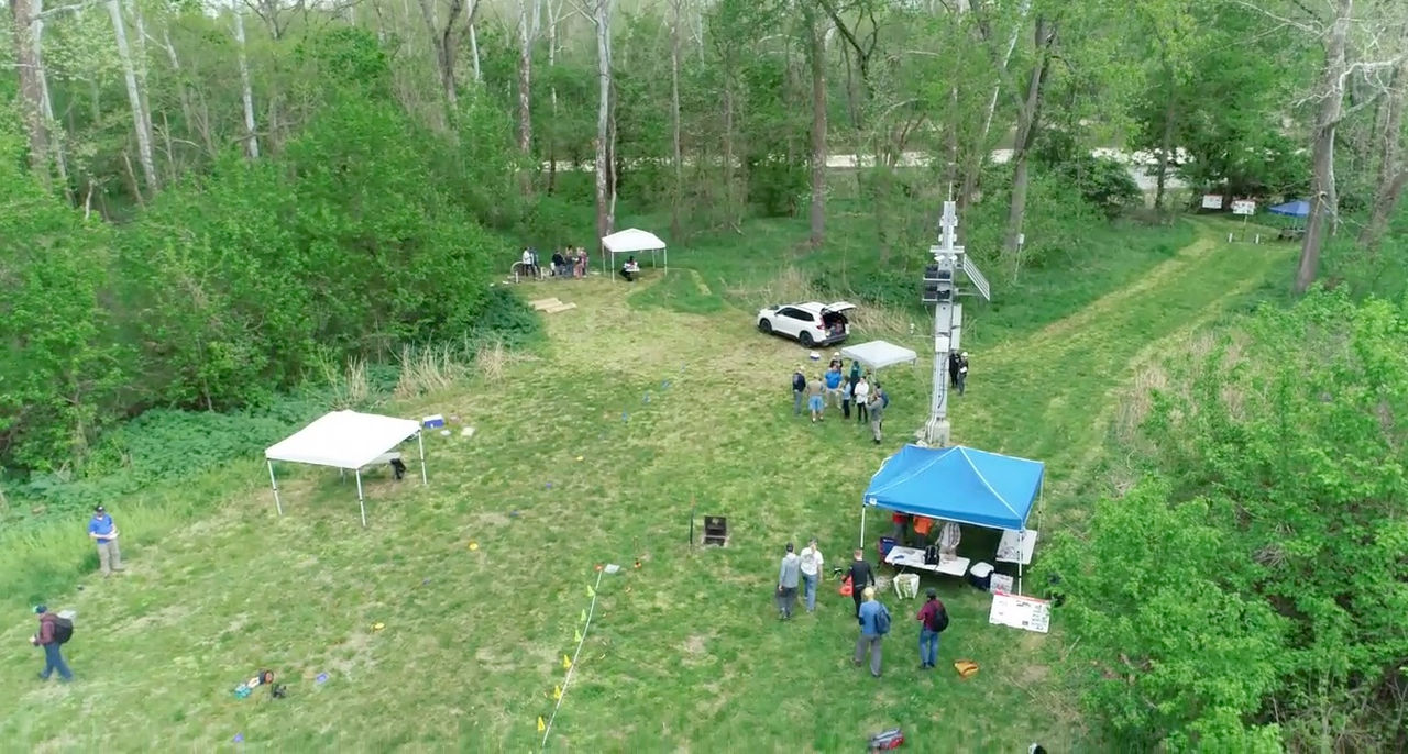 An aerial shot of UC's groundwater observatory depicts tents and vehicles and people working in a clearing in the woods.