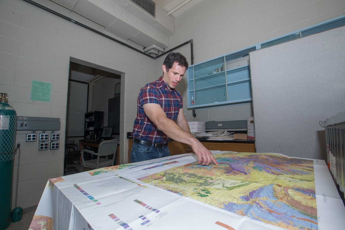 Daniel Sturmer points to a place on a colorful map.