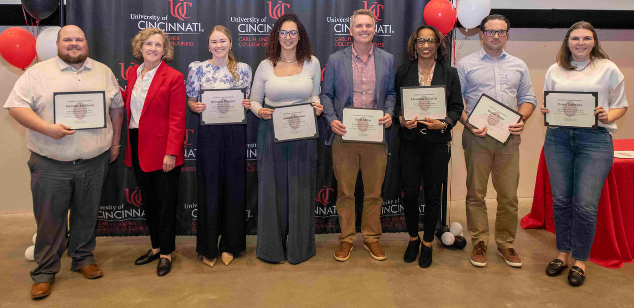 Member of the first year experience team hold their certificates with dean Lewis.