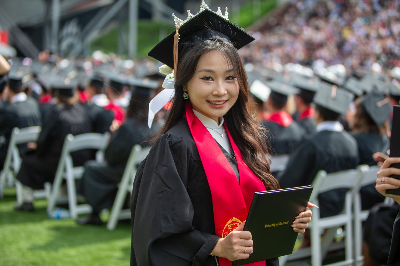 A UC graduate holds up her diploma
