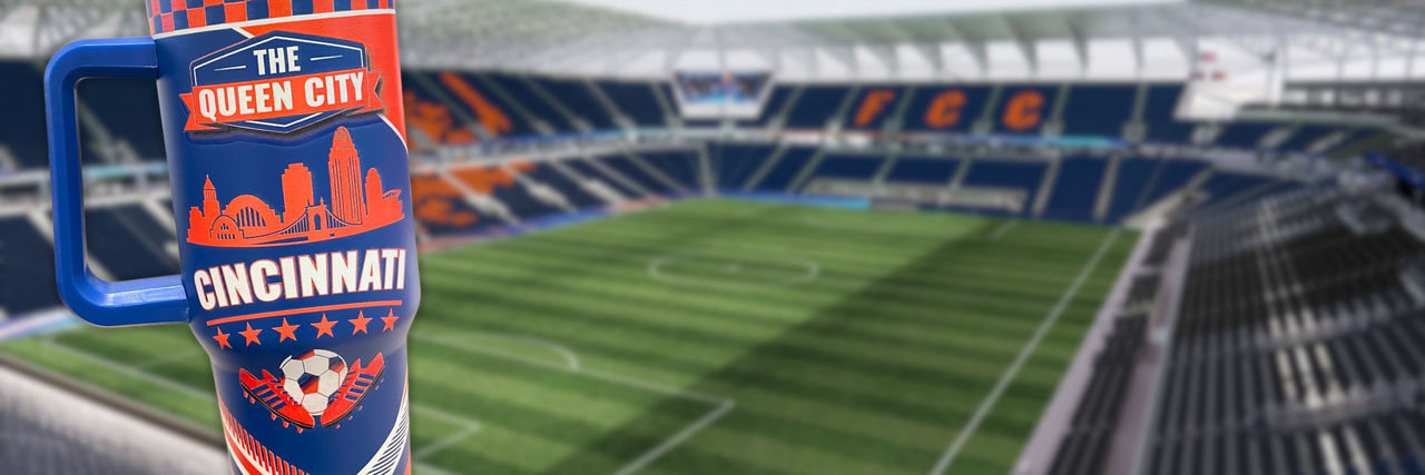 FCC branded tumbler in front of TQL stadium pitch