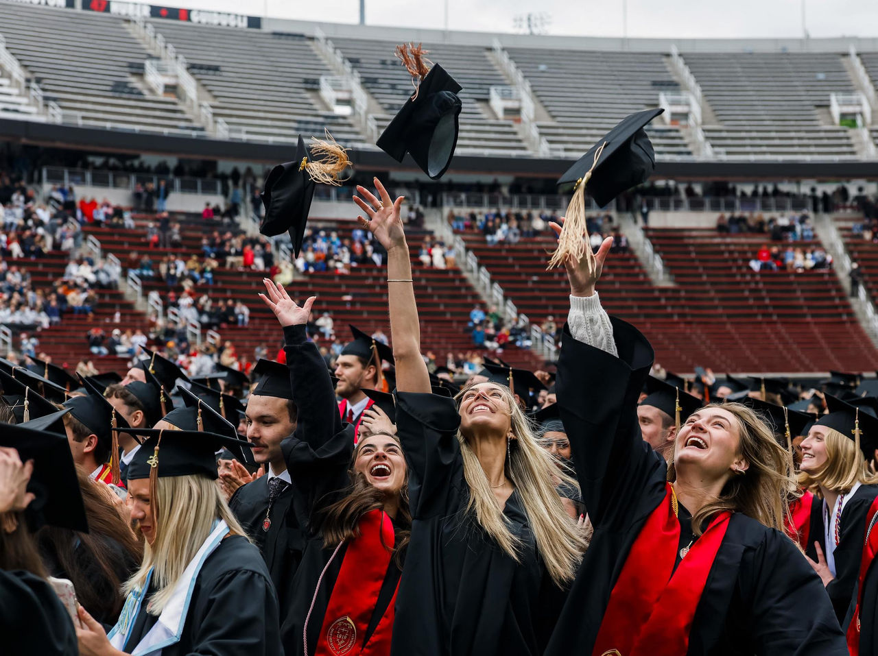 Students in graduation garb toss their caps in the air in Nippert Stadium during the University of Cincinnati’s record Spring 2026 commencement.