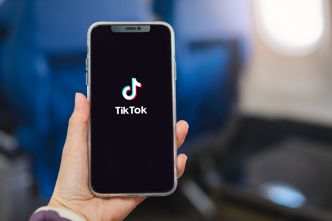 image of a hand holding a phone with the screen showing TikTok