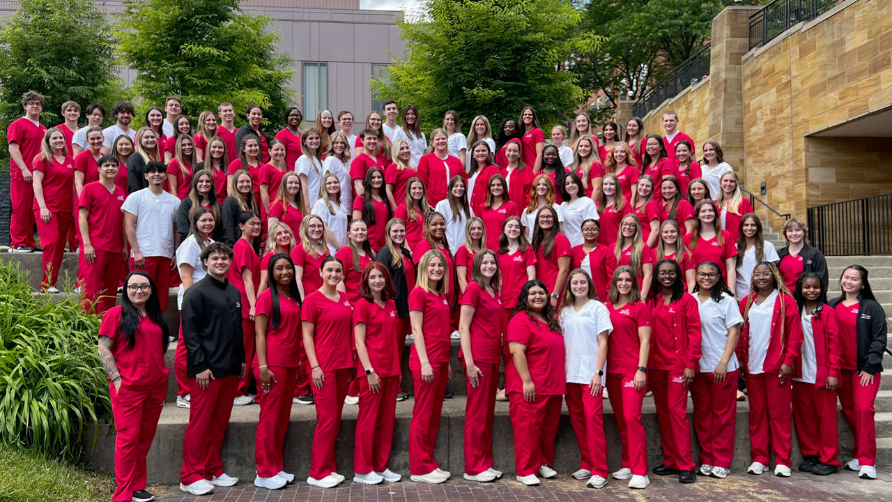 UC Nursing students wearing red scrubs standing in rows 