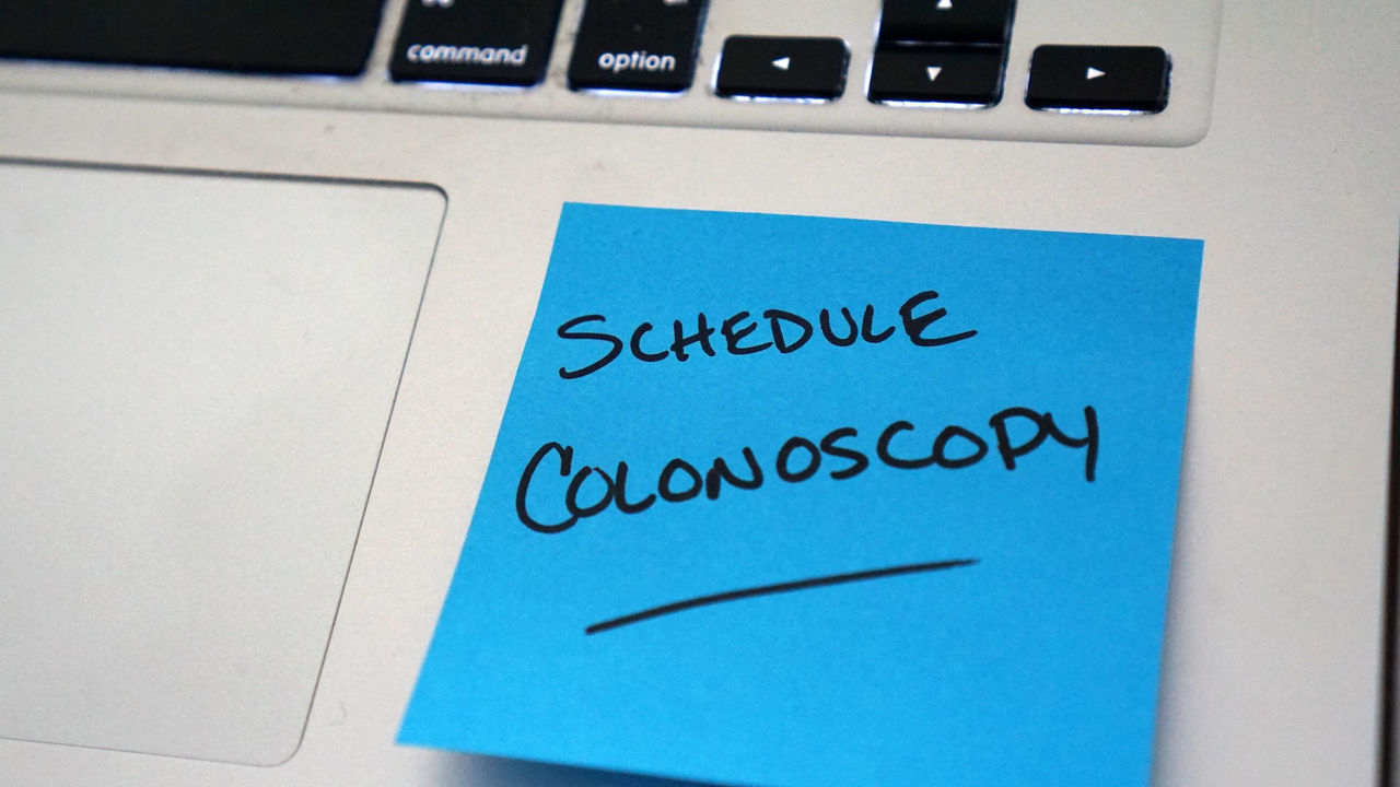 Blue sticky note that says schedule colonoscopy on laptop keyboard