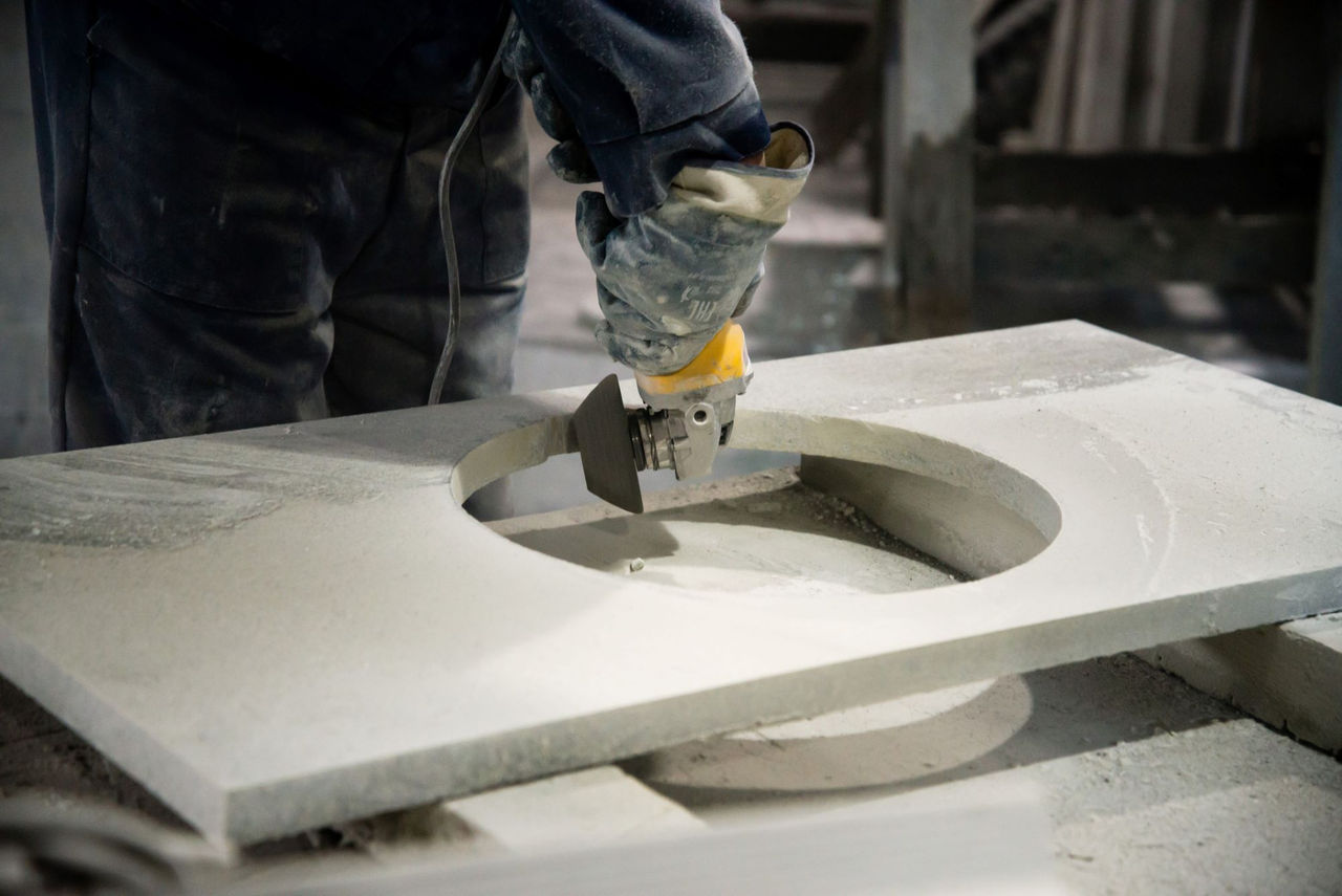 fabrication worker using a tool to cut engineered stone used in kitchen countertops