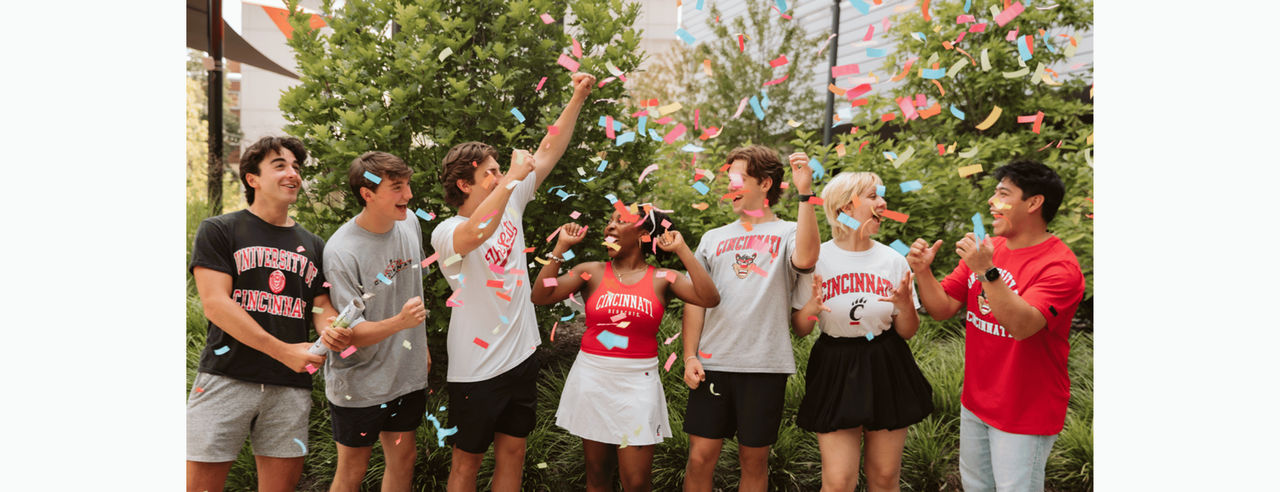 Group of UC students celebrating UC Day of Giving under confetti. 