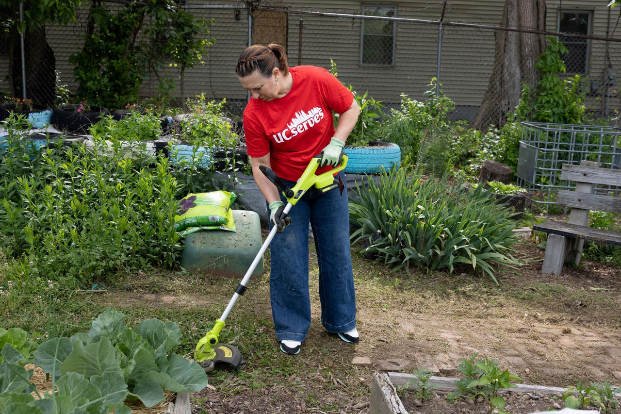 UC employee with a weed wacker in a community garden.