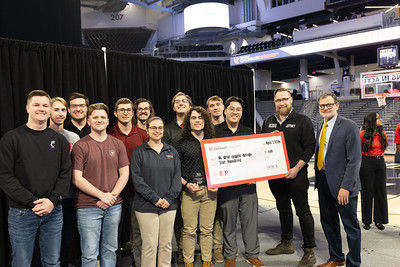 APOP student team poses with a giant check and a Lucius Q representative on stage at the CEAS EXPO. 