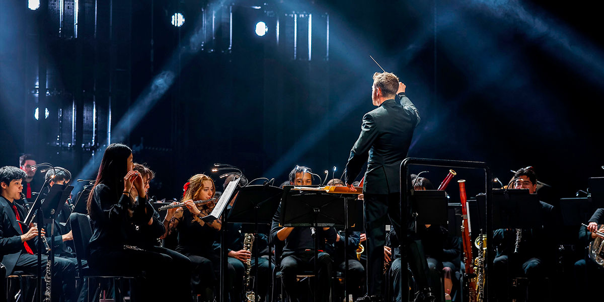 CCM Wind Symphony performs under dramatic blue lighting during the 2026 Moveable Feast event.