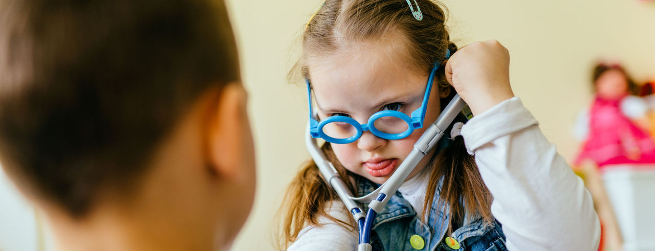down syndrome girl checking friend with toy sthetoscope