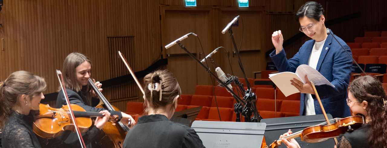Kevin Li conducts 4 women in a string quartet in an empty auditorium