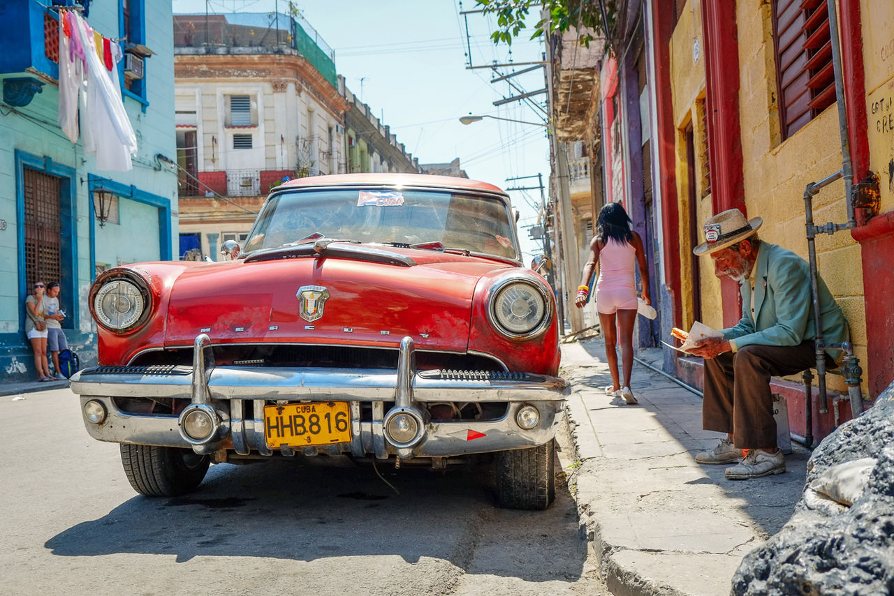 A city street in Cuba features a classic car. 