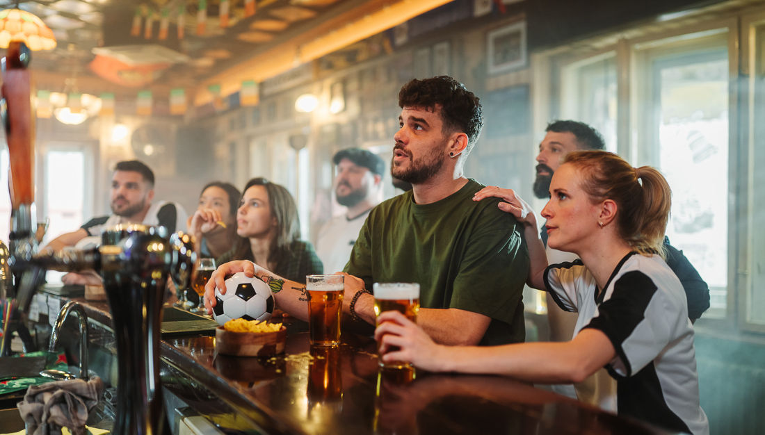 People gather at a bar to watch a soccer game with soccer ball on the barl
