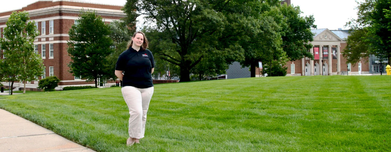 UC undergrad student Autumn Springston stands on the grass on Bearcat Commons in front of Swift Hall.