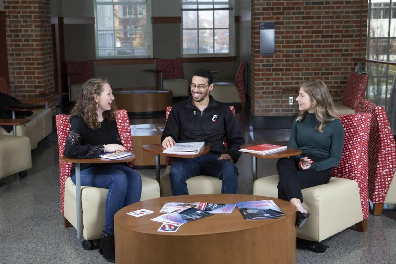 Three smiling students seated in CECH study area