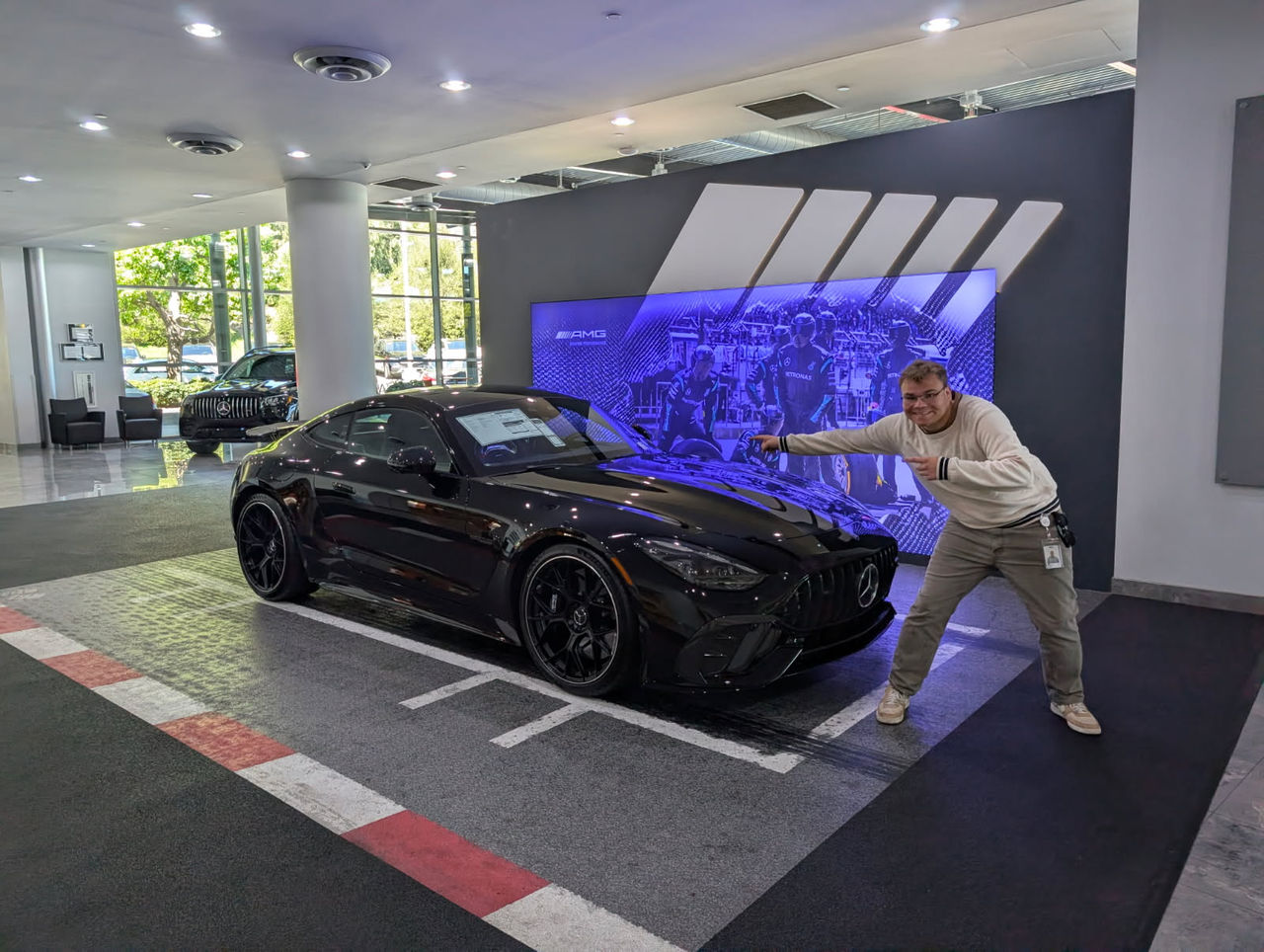 Sam Grove gestures to a Mercedes-Benz in a showroom. UC's nationally ranked cooperative education program helped the mechanical engineering student gain hands-on automotive engineering experience with Honda and Mercedes-Benz before graduation.