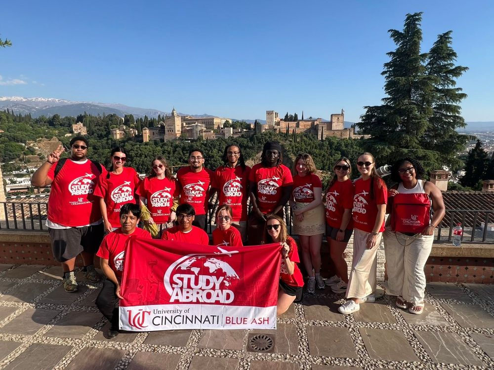 group of students gather with UC Blue Ash College Study Abroad flag in Granada
