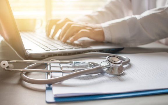 A doctor taking notes on a laptop.