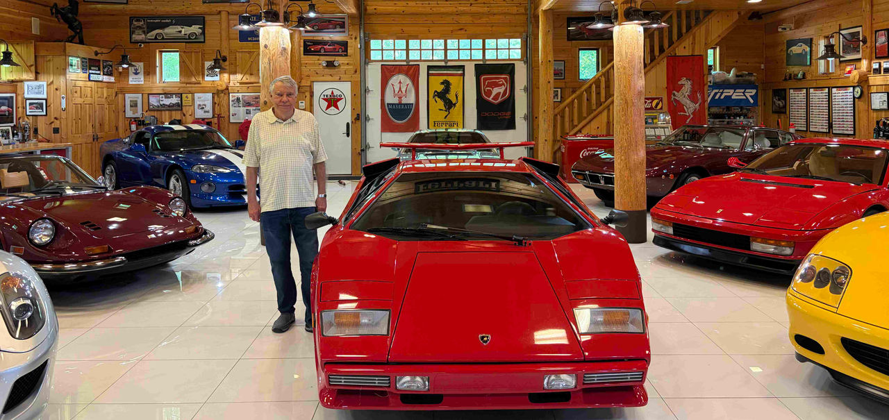 A man stands in a garage full of cars.