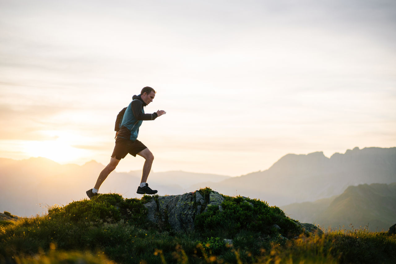 A young man runs on a mountain ridge at sunrise