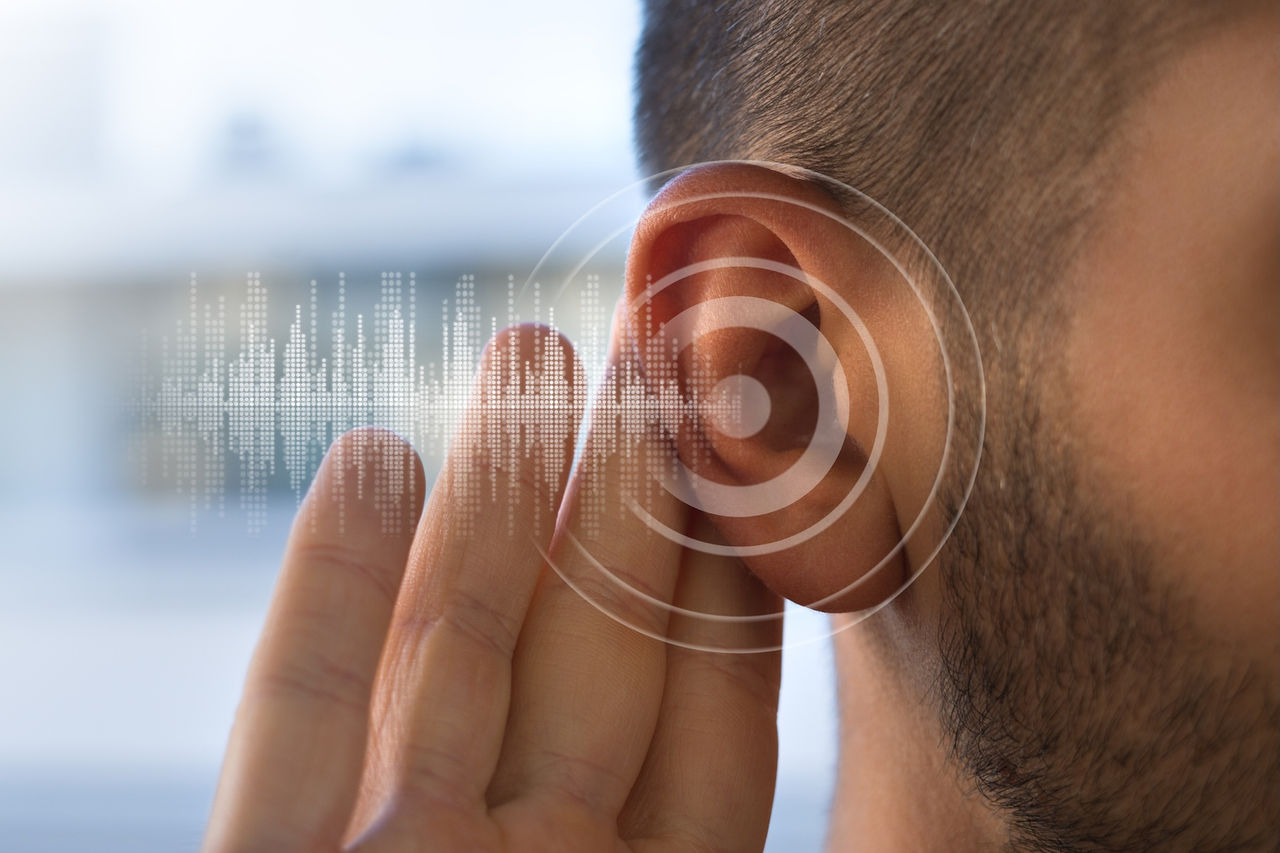 Person cups fingers around ear as sound waves travel out of ear 