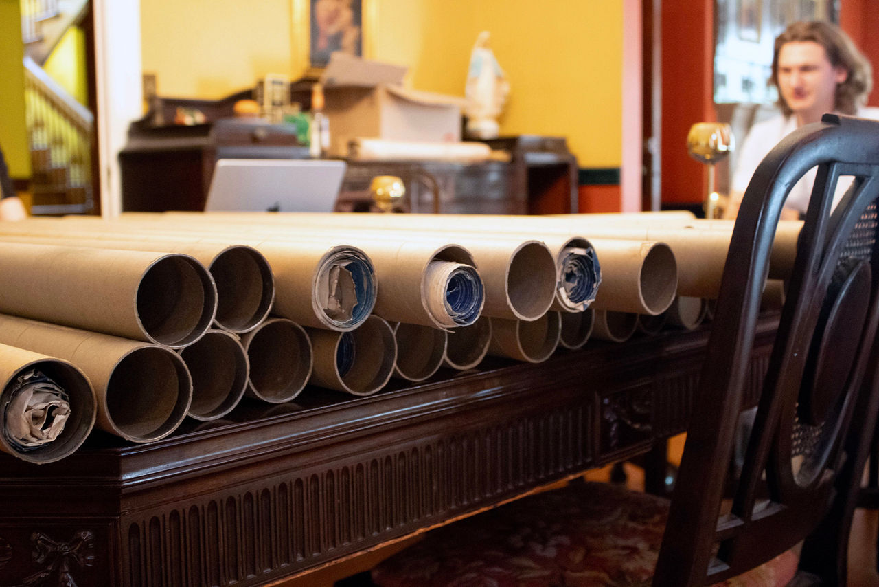In the foreground, rolled-up blueprints from the 1920s; in the background, UHP student Alex Smith