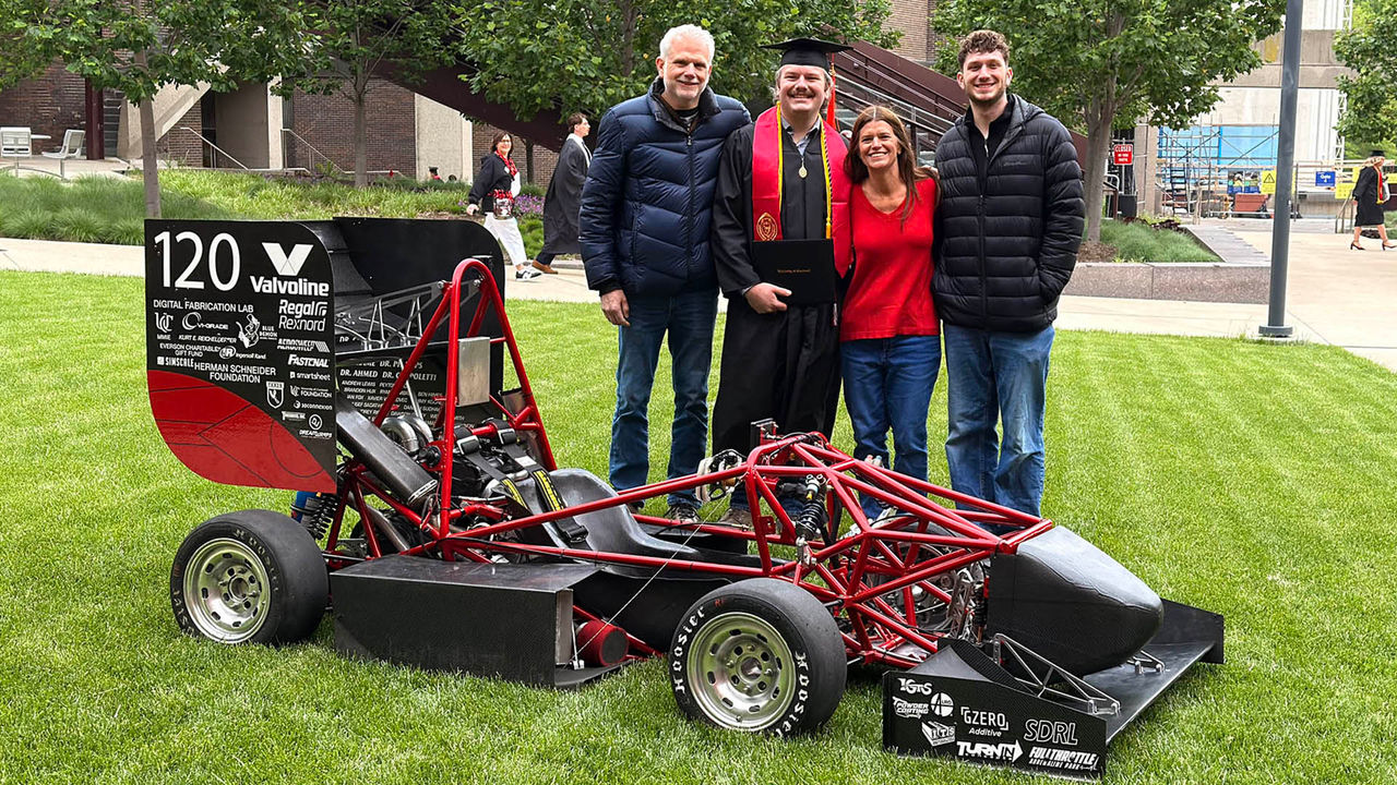 Family standing on UC campus in front of a car.