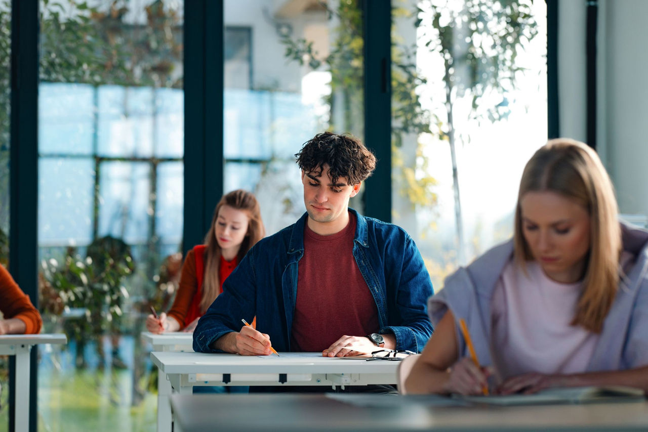 Image of four students sitting at their desks filling out tests.