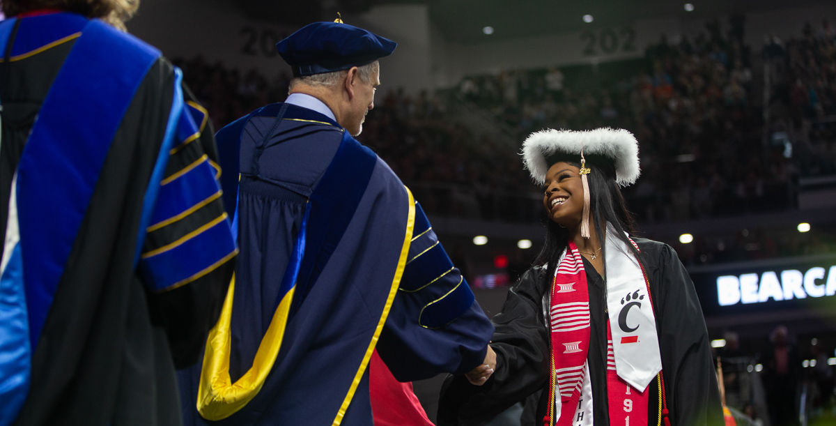 A UC grad accepts congratulations on stage at Fifth Third Arena.