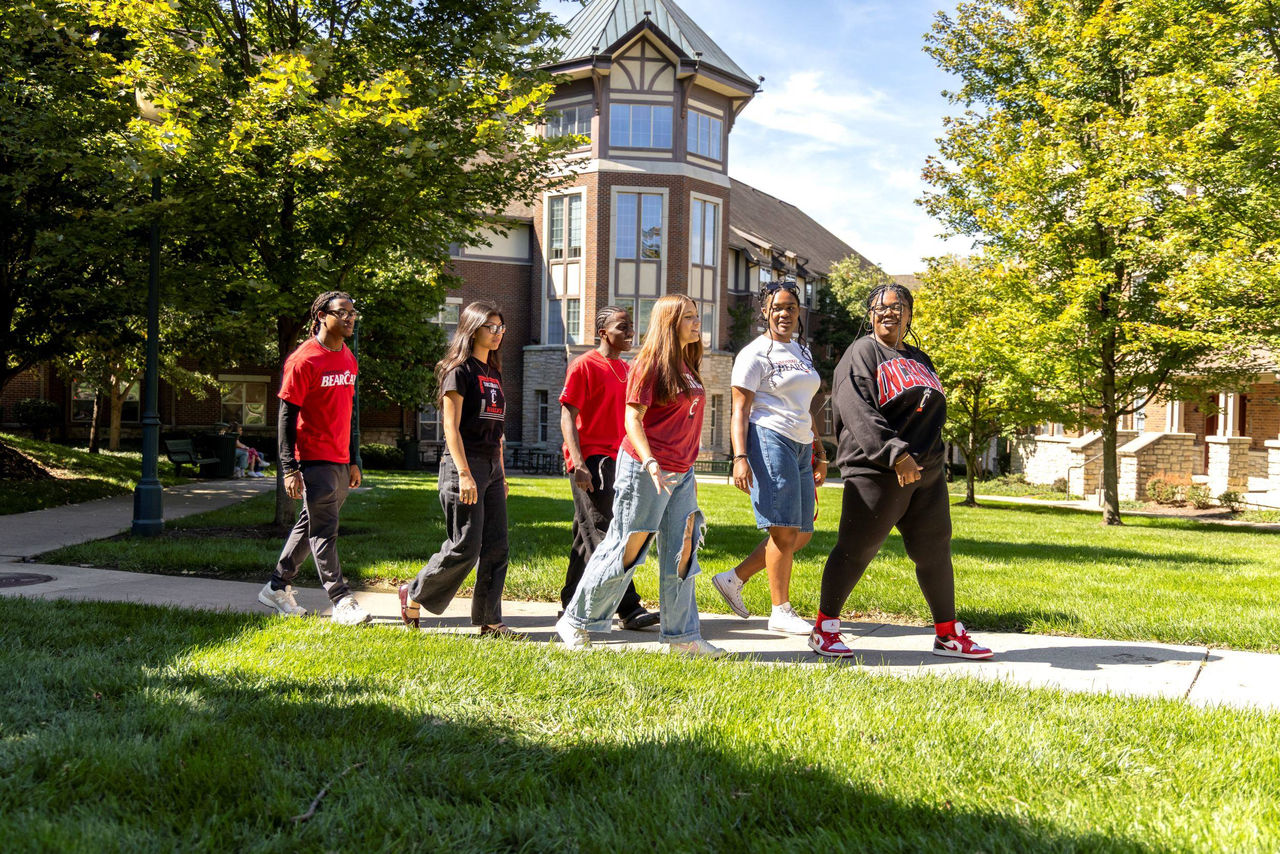 Six students walking in front of UC 1MPACT House. 