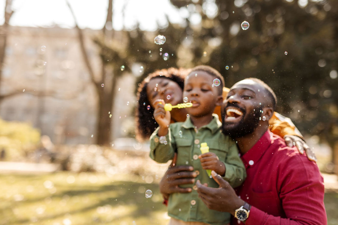 Mother, father and son blow bubbles and smile