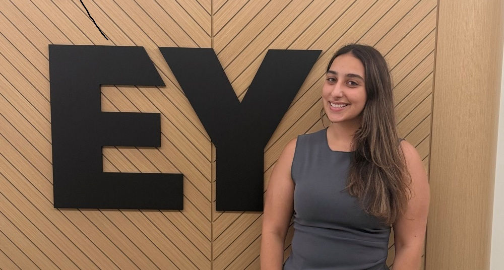 woman standing beside Ernst and Young logo in office