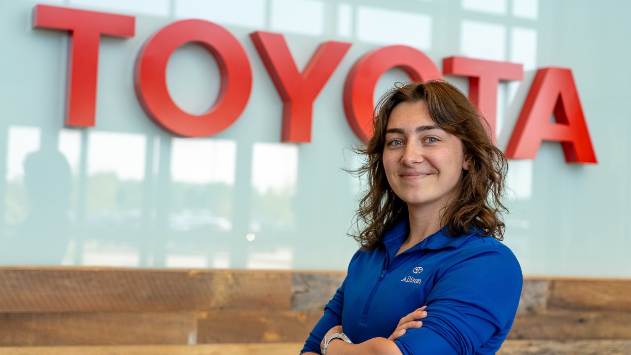 UC co-op student Allison Keith poses in front of a Toyota sign.