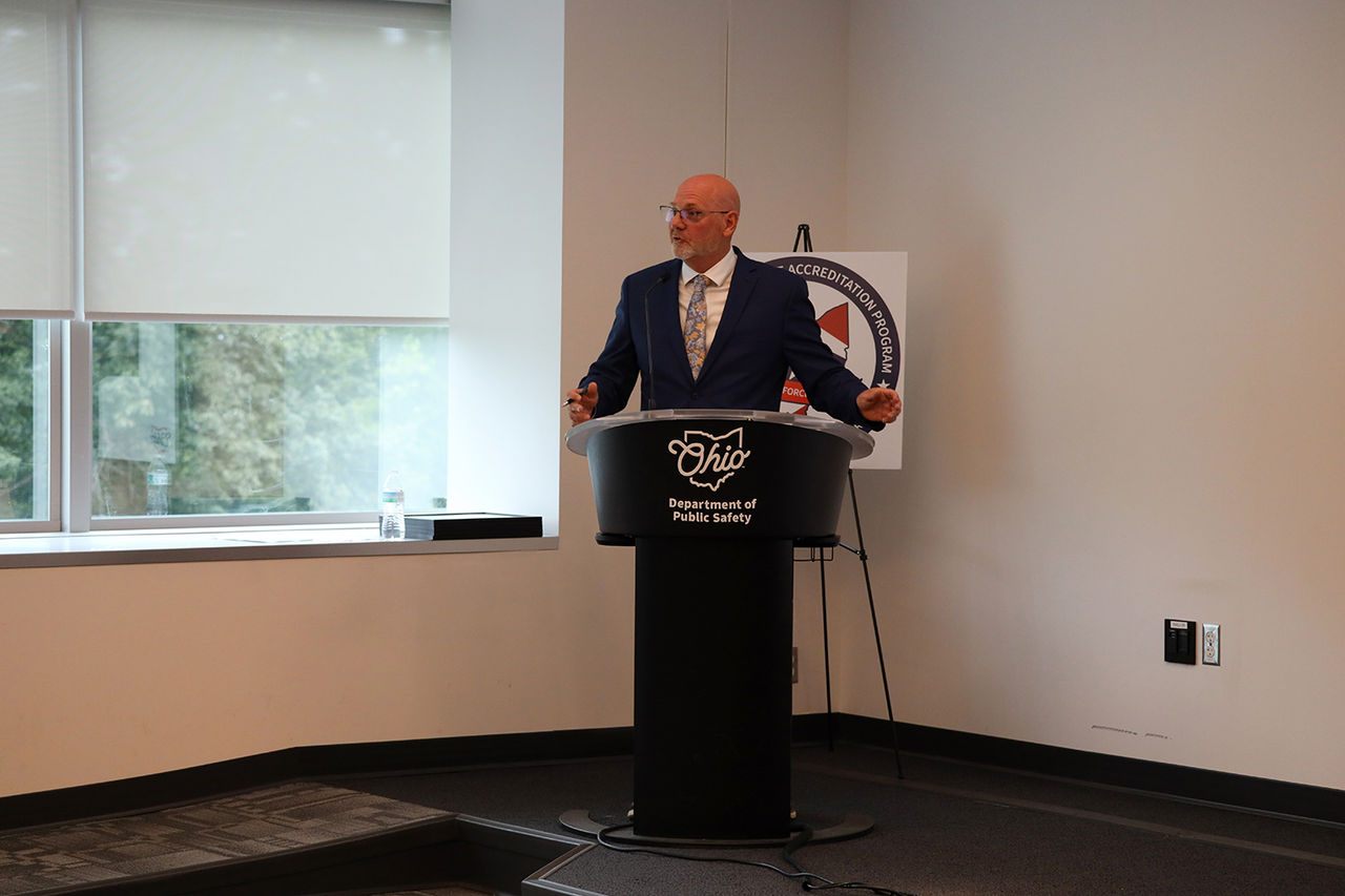 A man stands behind a podium and speaks.