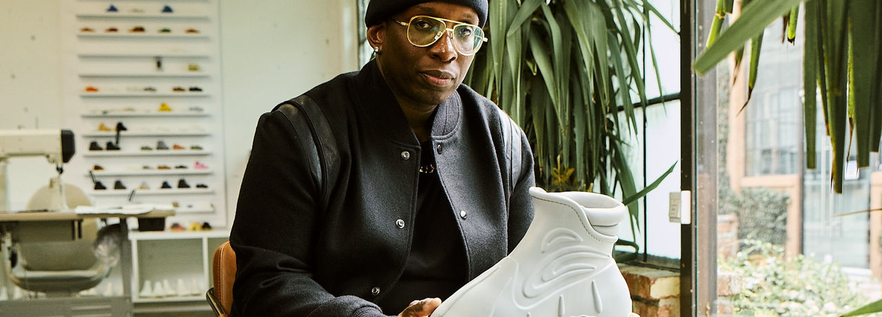 Image of Omar Bailey holding a shoe design by him
