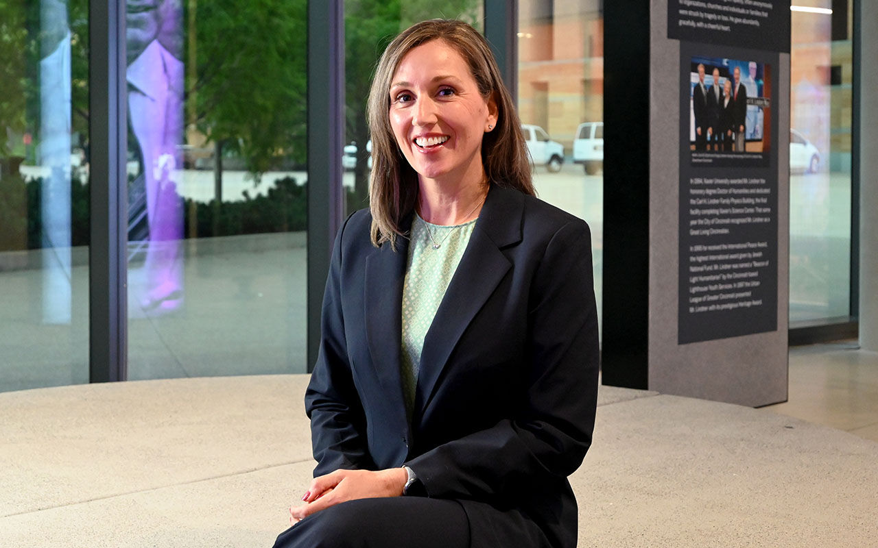 A woman in professional dress sits in the Lindner Legacy Area.