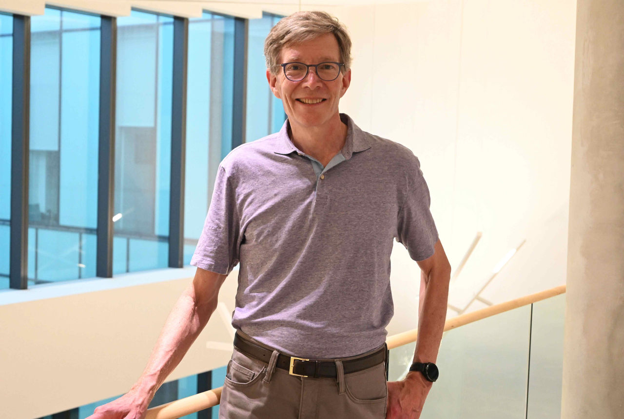 A man in a polo stands next to a railing in Lindner Hall
