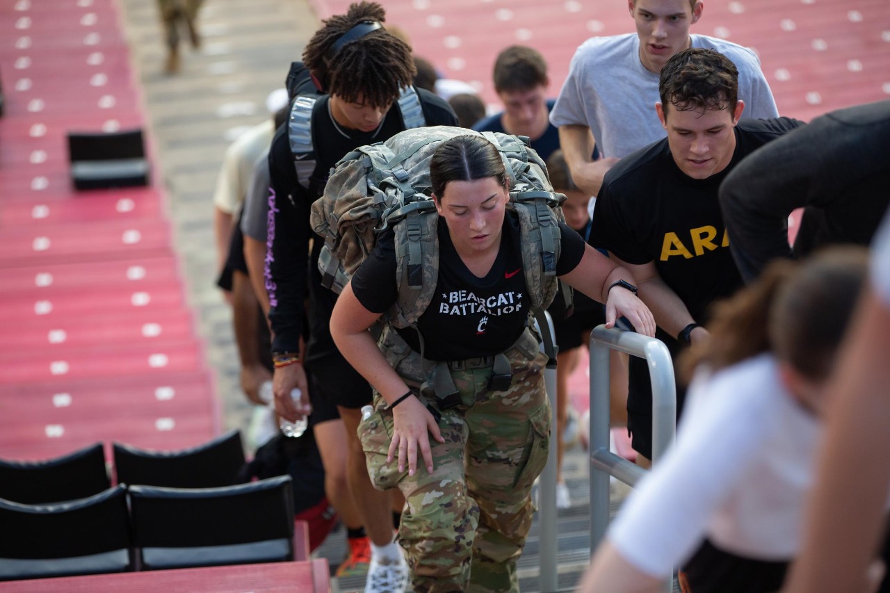 Members of UC's ROTC walk the stairs at Nippert Stadium while carrying a full rucksack.