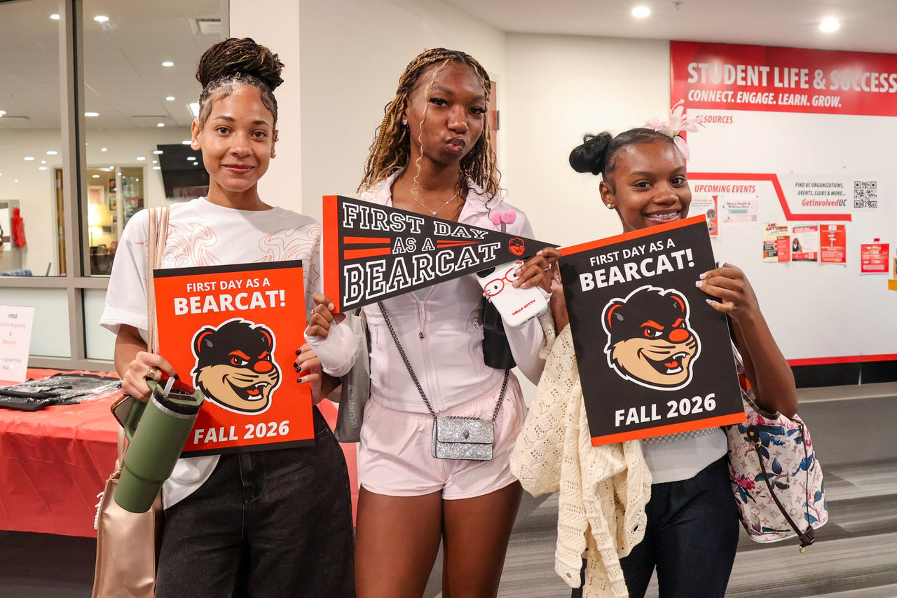 three female students holding UC Blue Ash College penant banners