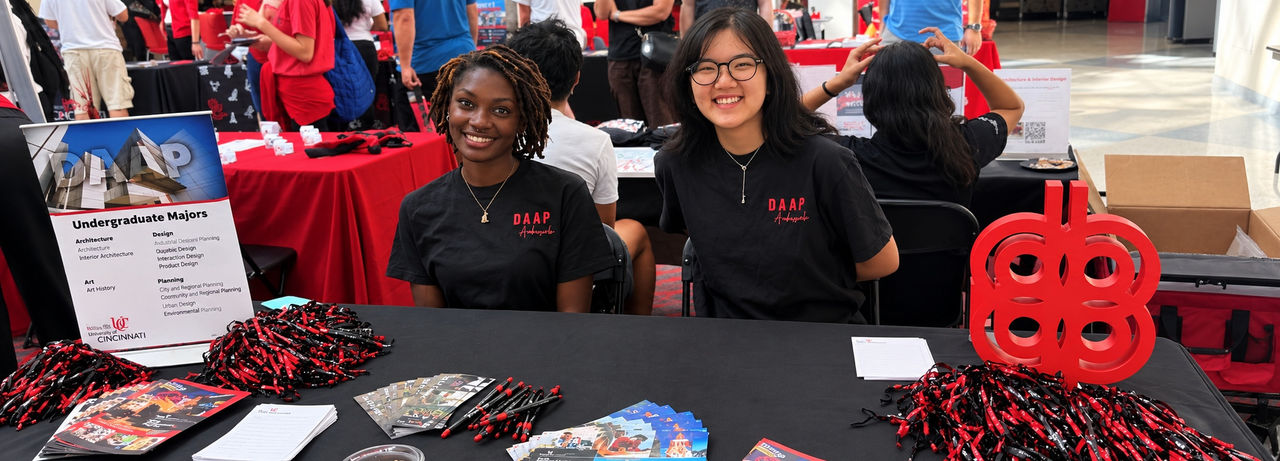 Two DAAP Ambassadors sit at an information table at the Tangeman University Center.