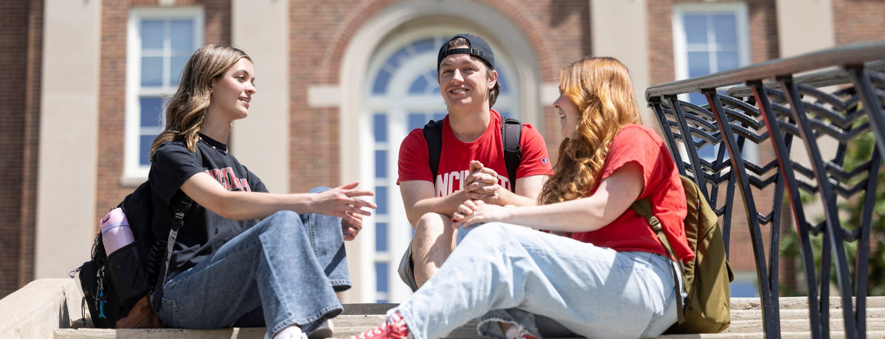 Three students sitting on stairs